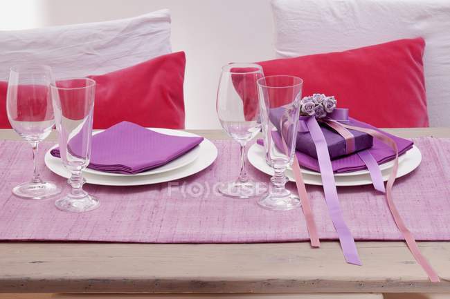 Накрытый стол с двумя местами настройки, подарок и посуда на день святого Валентина — стоковое фото