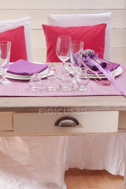 Накрытый стол с двумя местами настройки, подарок и посуда на день святого Валентина — стоковое фото