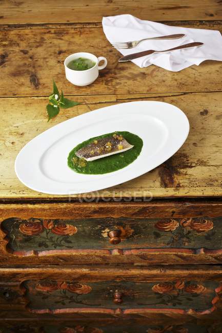 Vue surélevée du poisson d'omble sur les orties piquantes avec un bouillon de feuilles de quai — Photo de stock