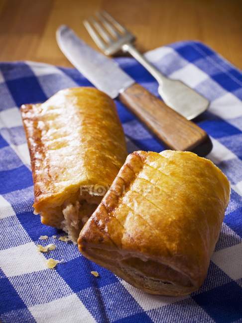 Closeup view of two sausage rolls with fork and knife on towel — Stock Photo