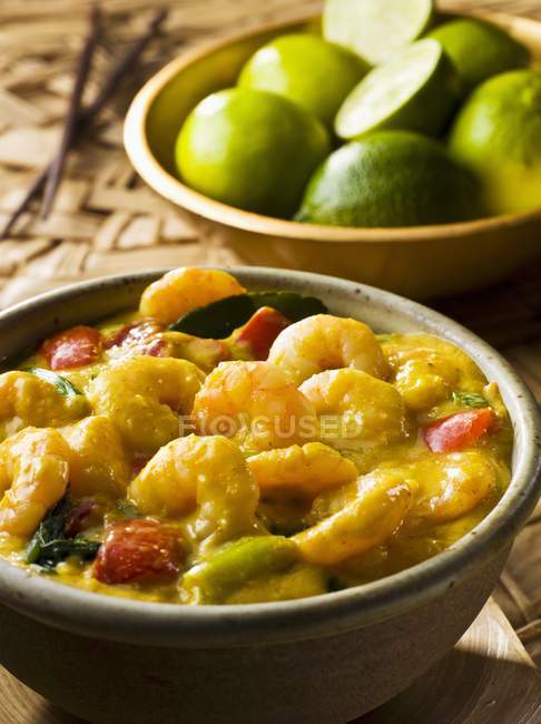 Vue rapprochée du curry de crevettes et des citrons verts dans les bols — Photo de stock