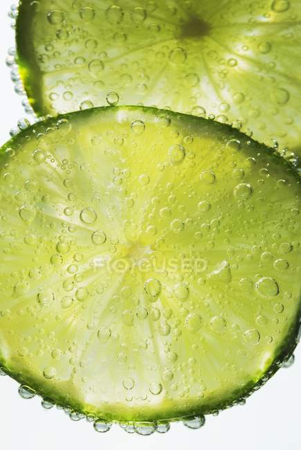 Lime slices in water — Stock Photo