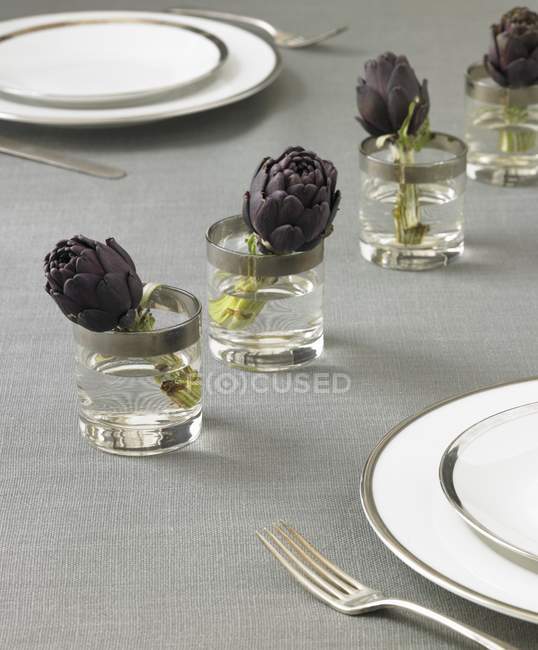 Table Setting with Artichokes in Glasses of Water — Stock Photo
