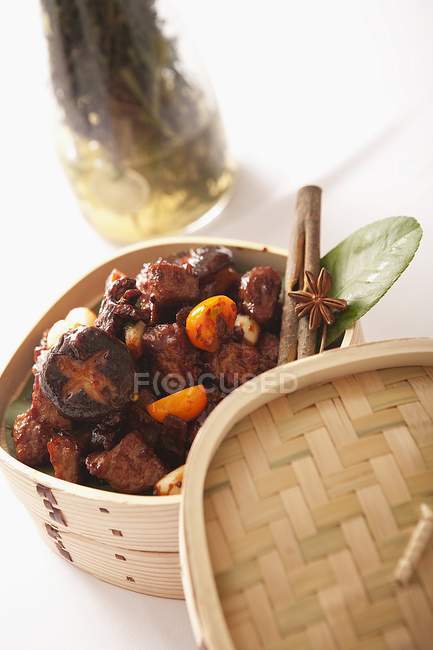 Closeup view of spiced chicken with mushrooms in a bamboo steamer — Stock Photo