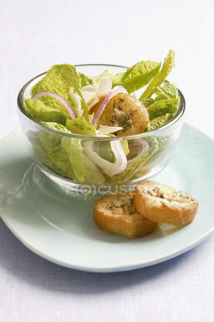 Caesar-Salat in Glasschüssel über Teller auf Tisch — Stockfoto