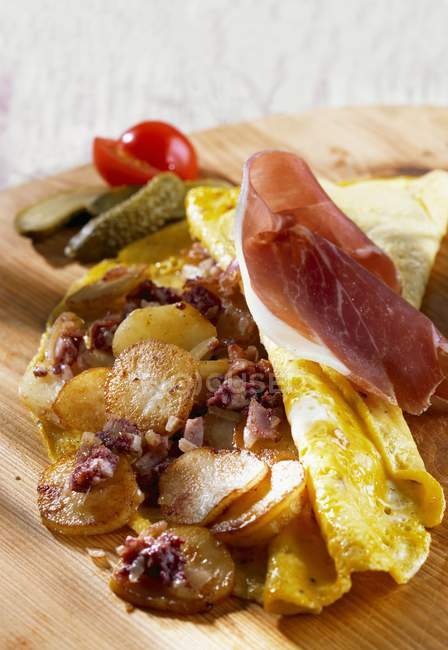A country omelette made with fried eggs and bacon over wooden desk — Stock Photo