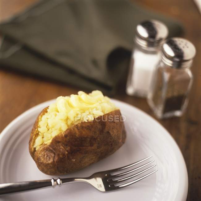 Patata al horno partida con mantequilla - foto de stock