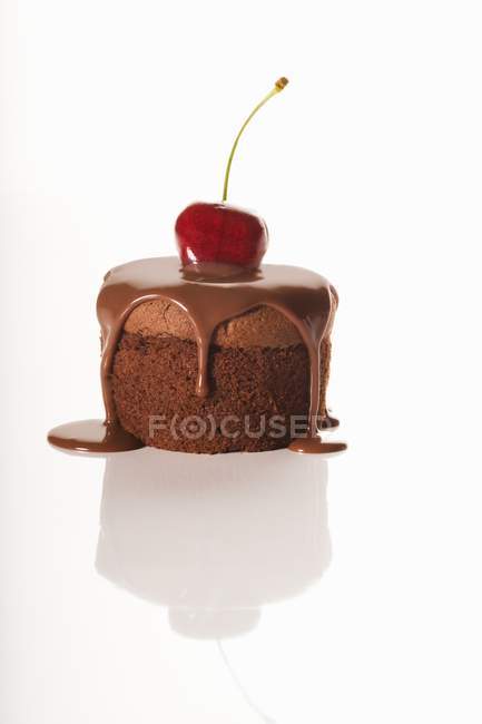 Closeup view of cake with chocolate sauce and cherry on white surface — Stock Photo