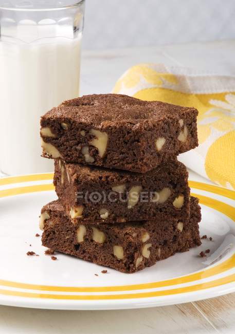Serving of walnut brownies stacked on plate — Stock Photo
