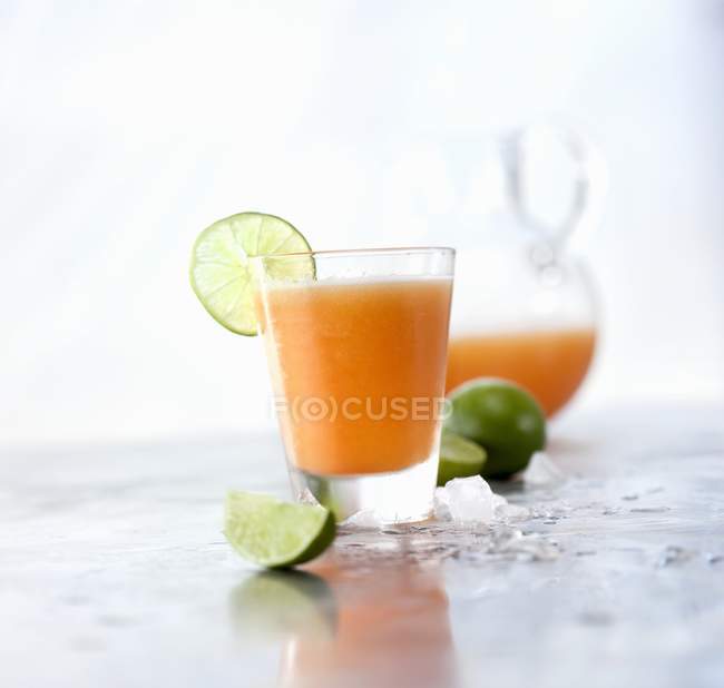 Closeup view of Cantaloupe Agua Fresca with lime garnish and pitcher — Stock Photo