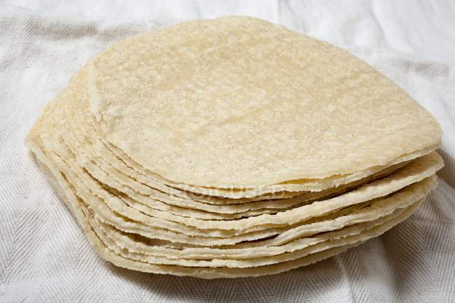 Vue rapprochée des tortillas de maïs empilées sur tissu blanc — Photo de stock