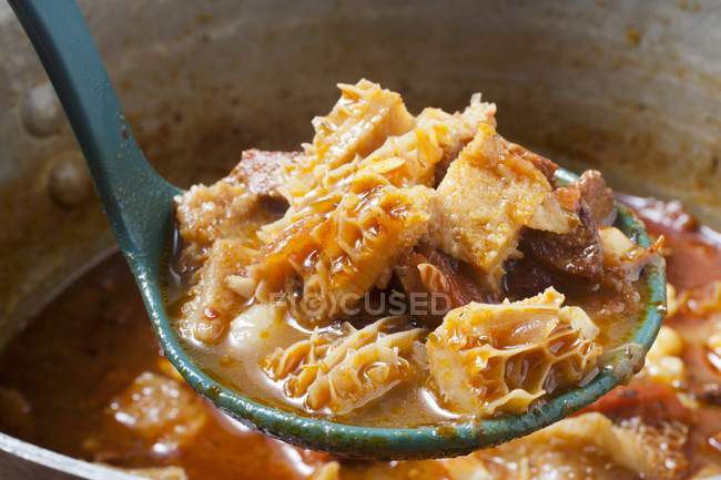 Closeup view of Menudo Colorado Mexican tripe stew in ladle and pot — Stock Photo
