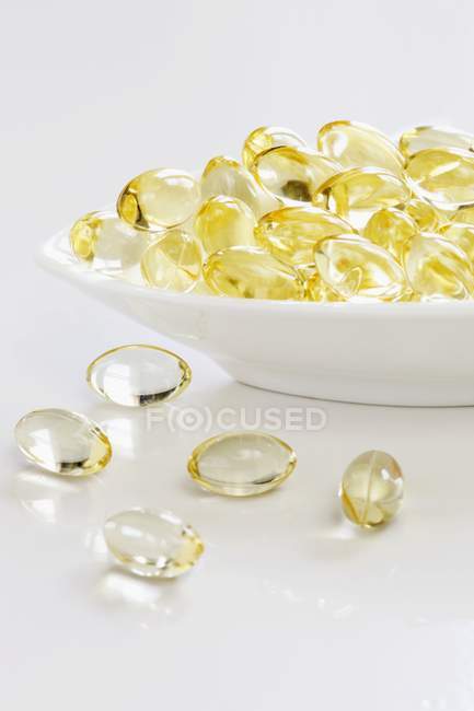 Closeup view of white bowl yellow capsules — Stock Photo