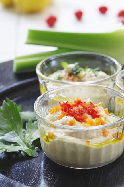 Schüssel Hummus mit gehackten Paprika und Selleriestangen auf Tablett — Stockfoto