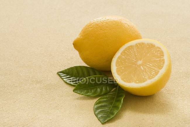 Limón fresco con la mitad y hojas - foto de stock