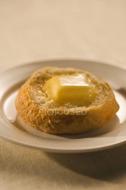 Closeup view of cut biscuit with melting butter on saucer — Stock Photo