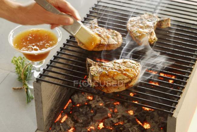 Chops on grill with sauce — Stock Photo