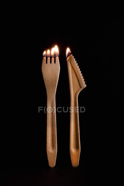 Closeup view of burning wooden fork and knife on black background — Stock Photo