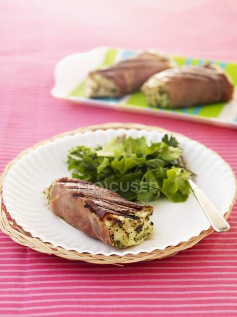 Vue rapprochée du flétan enveloppé dans du jambon avec une salade de feuilles mélangées — Photo de stock