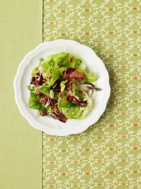 Vista de primer plano de ensalada de hojas mixtas con tocino en el plato - foto de stock