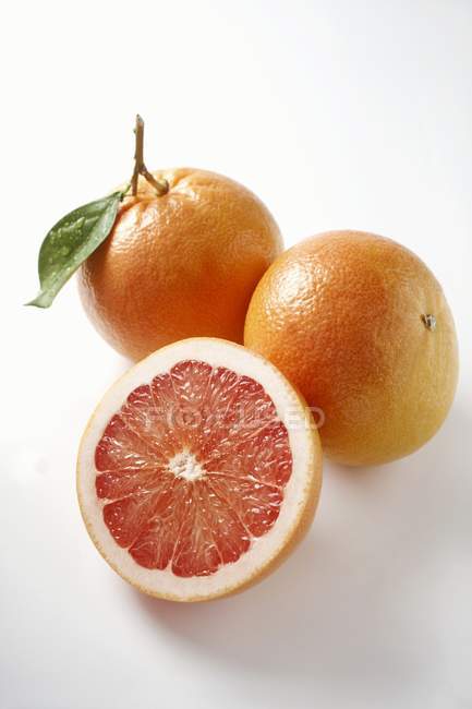 Rote Grapefruits mit Hälfte und Blättern — Stockfoto