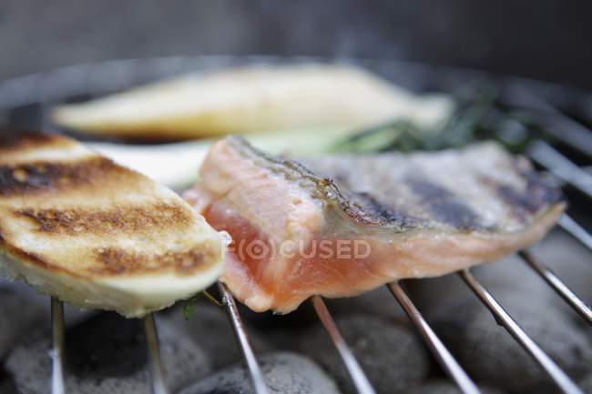 Vista de cerca de los filetes de pescado a la parrilla en rack sobre carbón - foto de stock