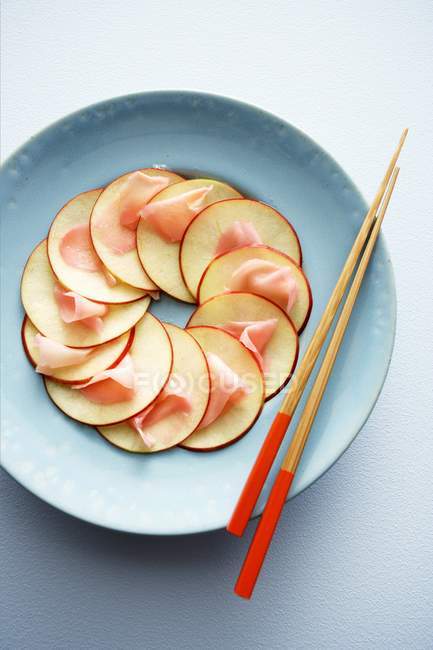 Vue du dessus du carpaccio de pomme avec gingembre et baguettes sur assiette — Photo de stock