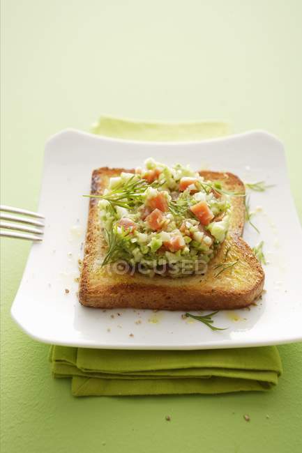 Una fetta di pane tostato condito con asparagi tatar su piatto bianco sopra asciugamano verde — Foto stock