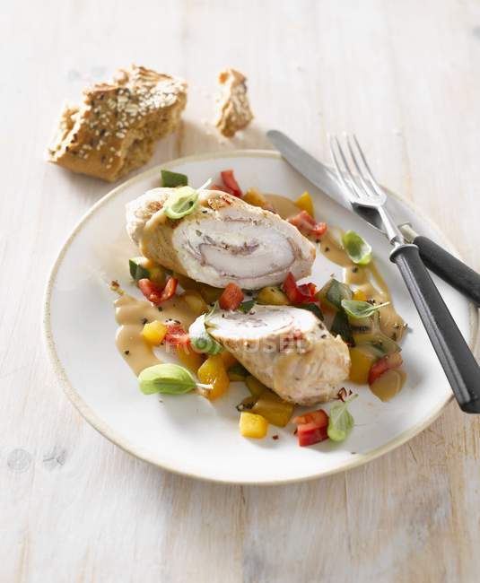 Involtino di tacchino con verdure su piatto bianco con forchetta e coltello — Foto stock