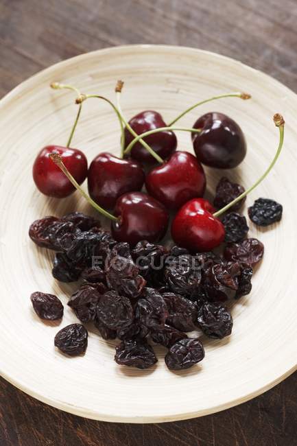 Plate of fresh and dried cherries — Stock Photo