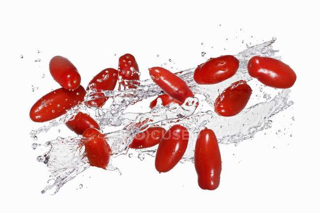 Tomates prunes aux éclaboussures d'eau — Photo de stock