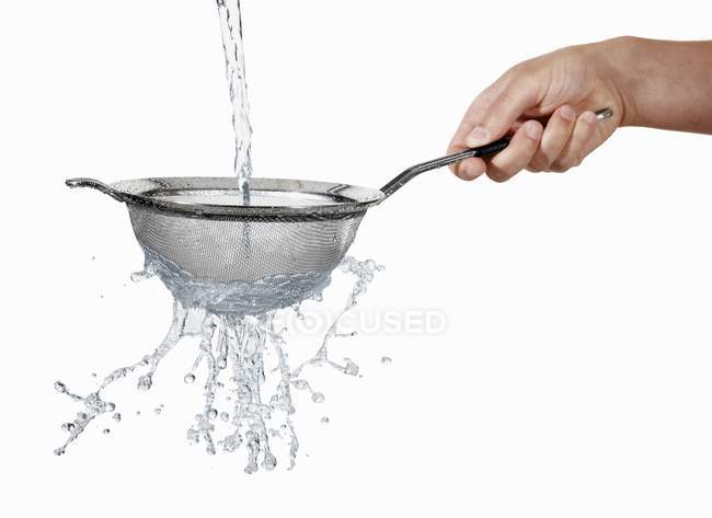 Hand holding a colander with stream of water running through — Stock Photo