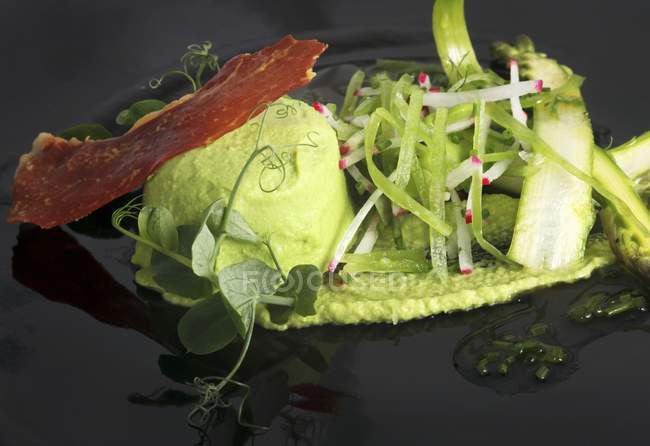 Mushy peas with bacon and green asparagus on black surface — Stock Photo