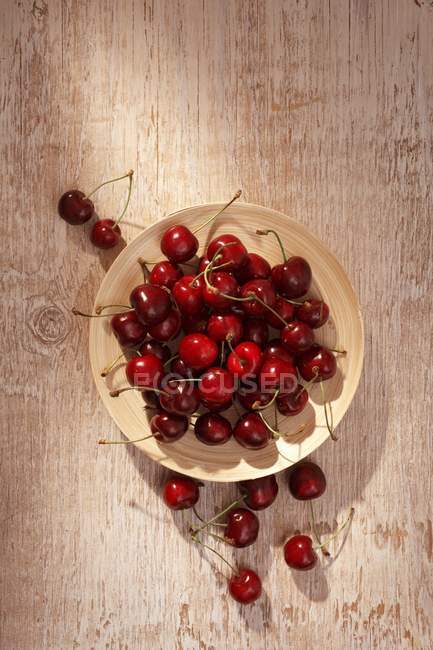 Holzteller mit roten Kirschen — Stockfoto
