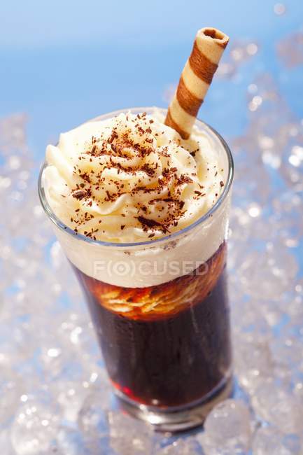Closeup view of iced coffee with cream and a wafer roll — Stock Photo