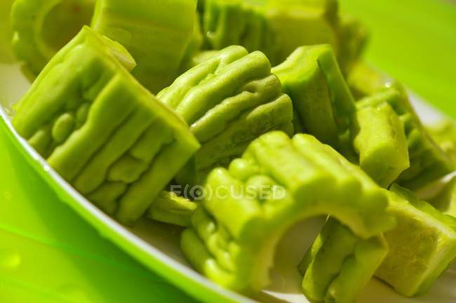 Zucca amara affettata su piatto verde su superficie verde — Foto stock