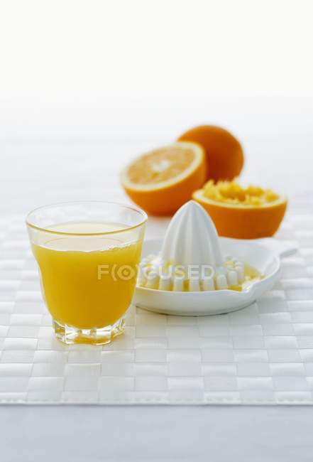 Vidro de suco de laranja com espremedor de frutas cítricas — Fotografia de Stock