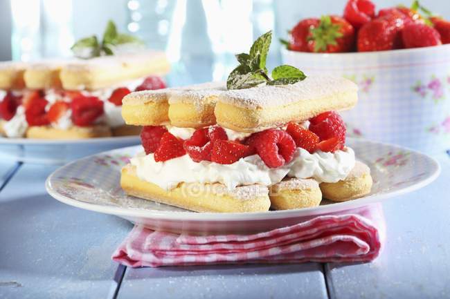 Крупним планом вид шаруватий десерт з губчастими пальцями, вершками та ягодами — стокове фото