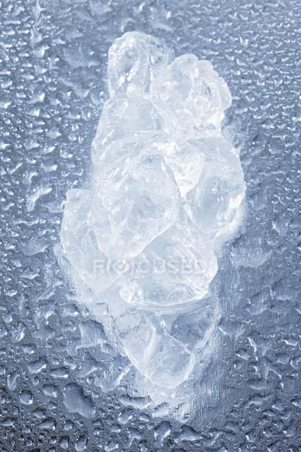Primer plano vista superior de un trozo de hielo sobre una superficie húmeda - foto de stock