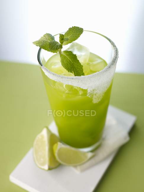 Closeup view of Green Dream cocktail with ice cubes, mint and lime wedges — Stock Photo