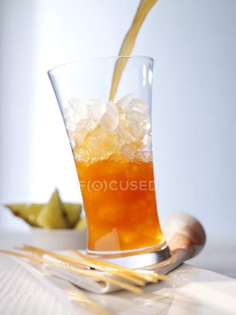 Vista da vicino di versare cocktail di frutta a bicchiere con ghiaccio — Foto stock