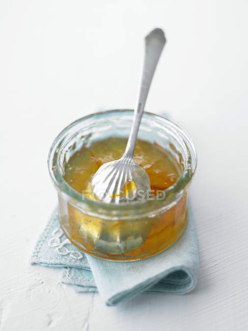 Vista de cerca de mermelada de naranja en un plato de vidrio con una cuchara - foto de stock
