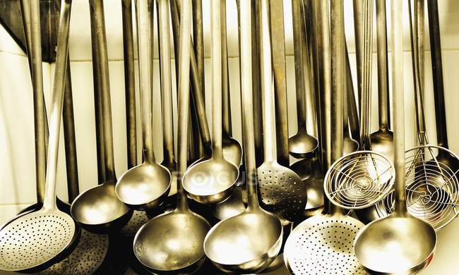 Closeup view of hanging ladles and strainer spoons row — Stock Photo