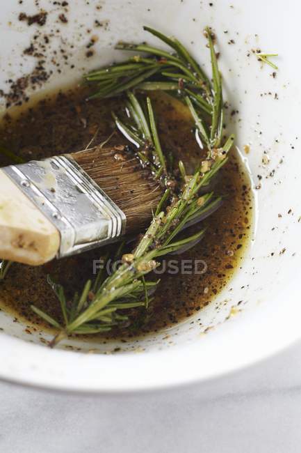 Marinada de alecrim em uma tigela com uma escova de bastão — Fotografia de Stock