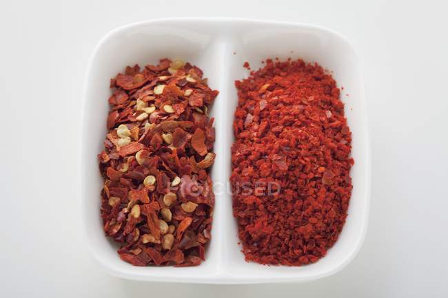 Top view of Chilli flakes in halved white dish — Stock Photo