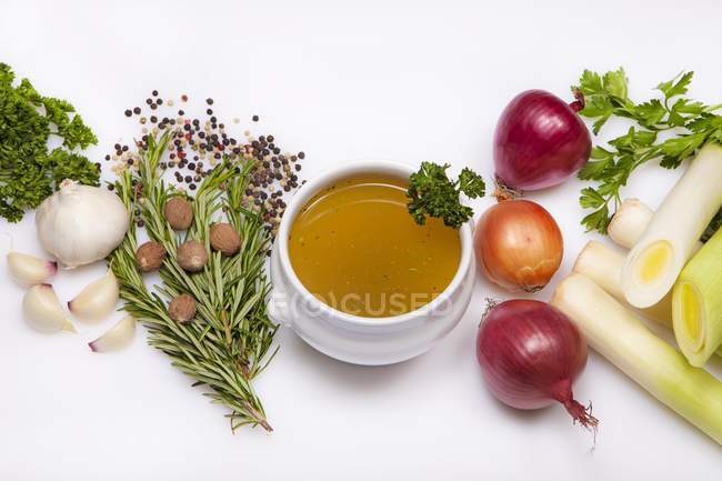 Suppenschale mit Gemüsebrühe und Zutaten auf weißem Hintergrund — Stockfoto