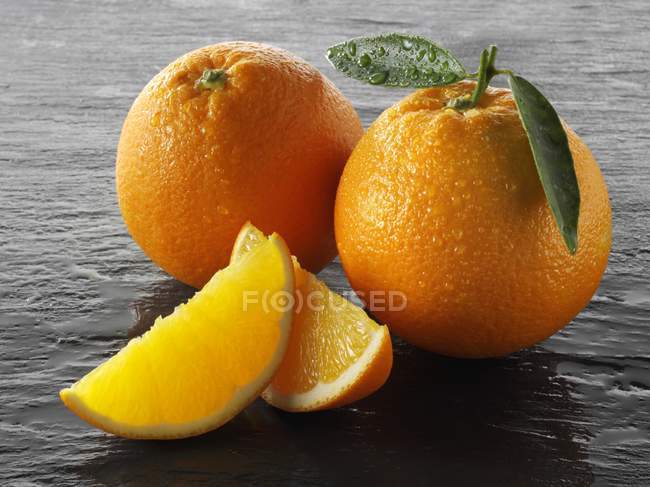 Fresh oranges with wedges — Stock Photo