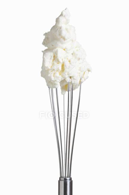 Closeup view of whipped cream on whisk on white background — Stock Photo