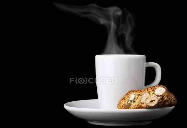 Vista close-up de Biscotti e uma xícara de café expresso contra um fundo preto — Fotografia de Stock