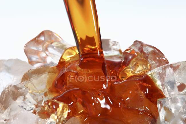 Closeup view of pouring herbal liqueur over ice — Stock Photo